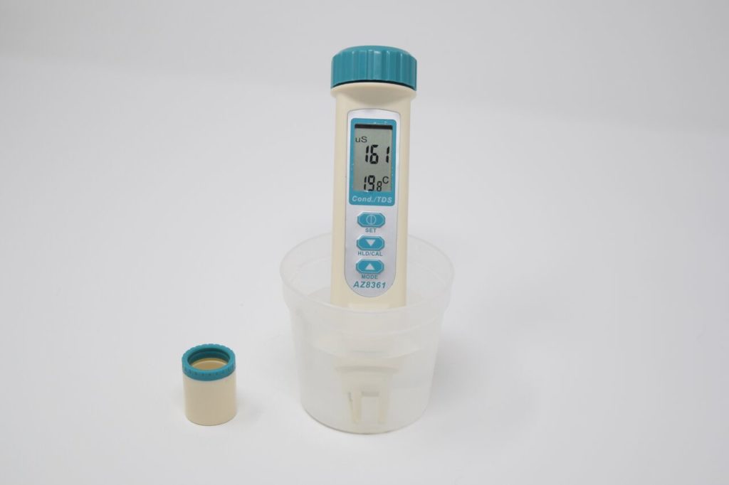 A digital conductivity probe measuring a sample of water. The conductivity measurement is 161 µS/cm, and the temperature is 19.8 degrees celsius 