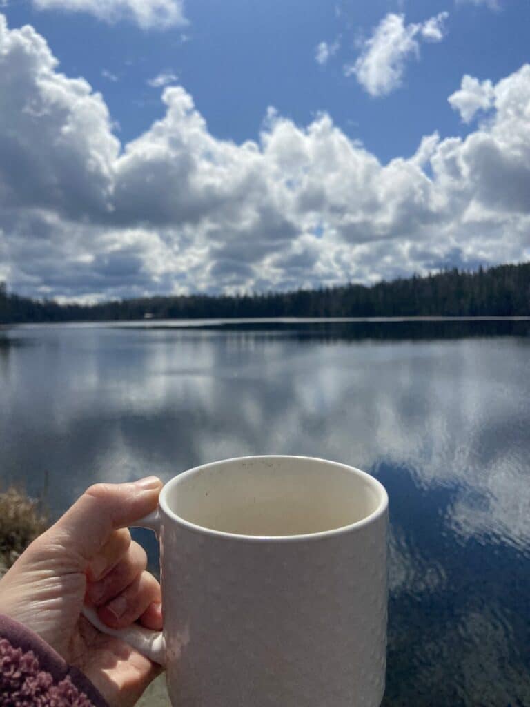 Coffee cup in front of a lake. We recommend this to make Mondays better!