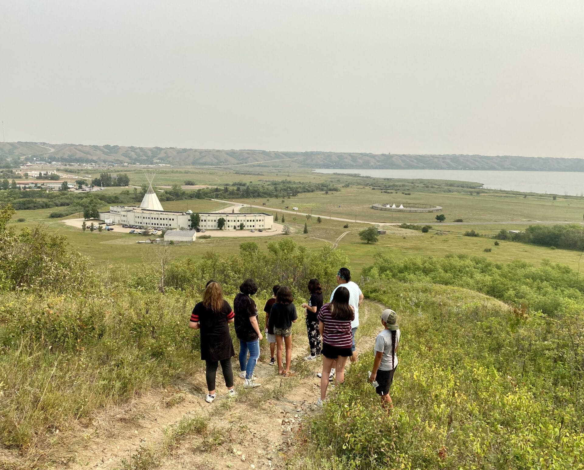 A group of camp attendees look out over the Treaty 4 Governance Centre and Qu'appelle Valley. 